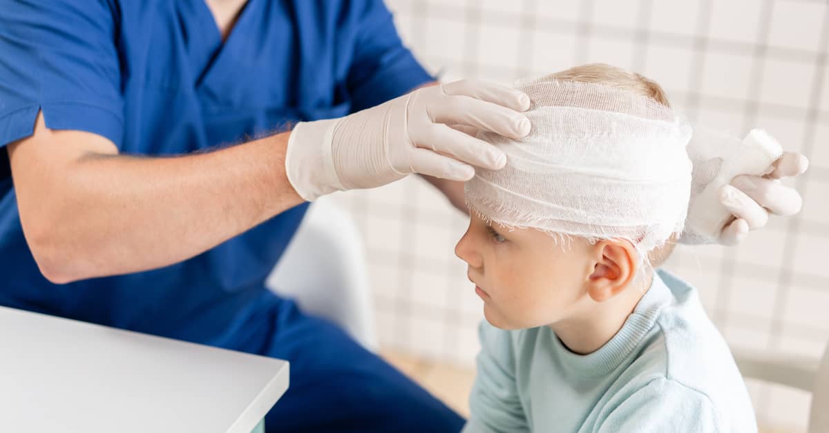 Doctor bandaging a child's head after a transport accident | Henry Carus + Associates