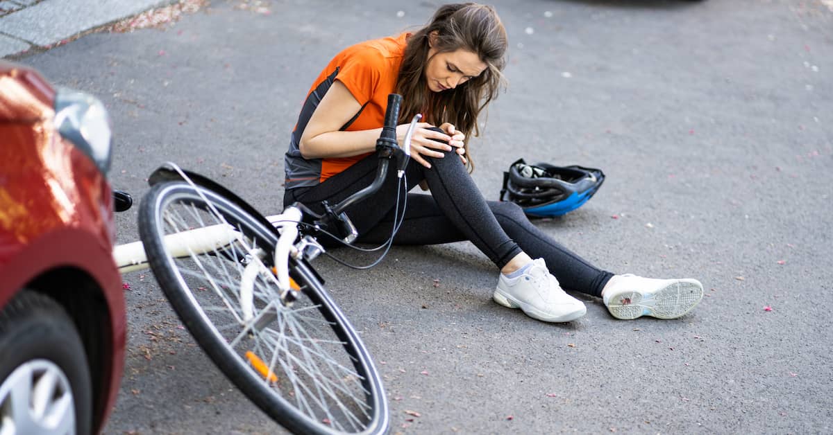 woman with injured knee lying on the ground after a bike accident