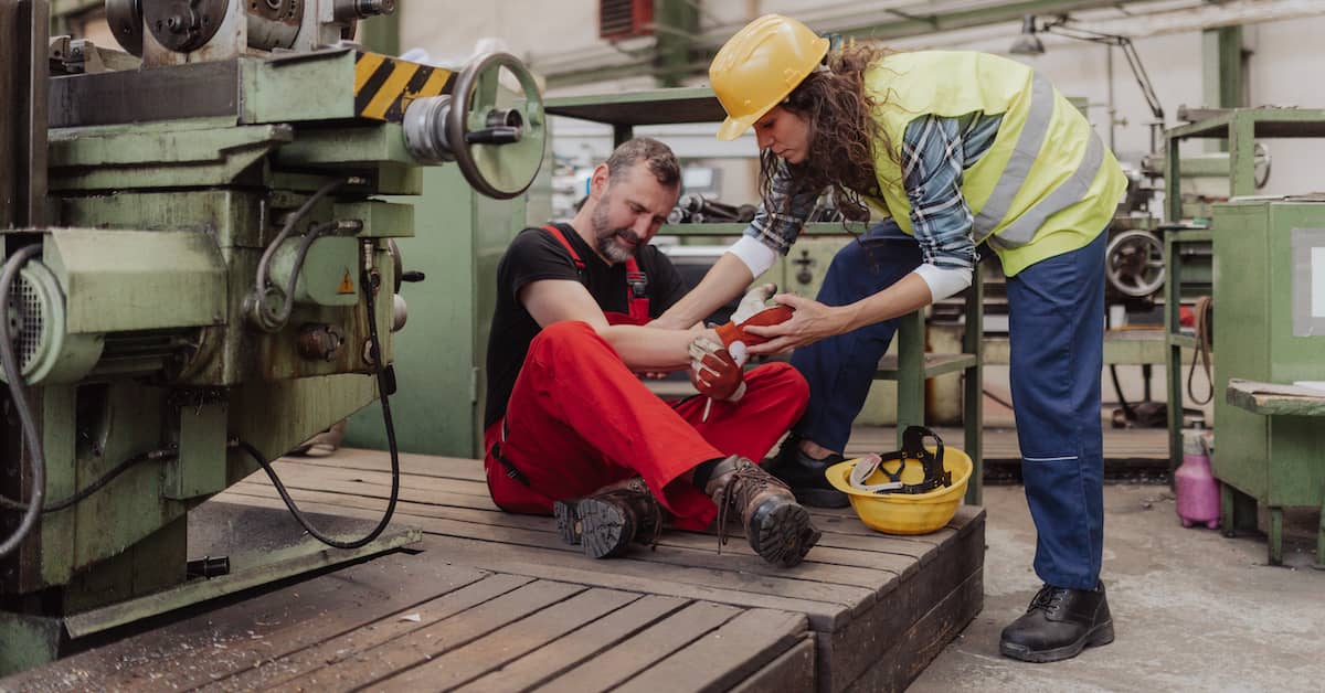 injured male factory worker being assisted by female coworker