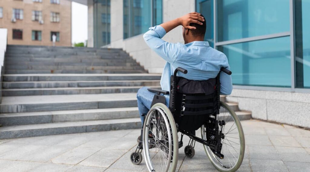 Disabled man in wheelchair unable to enter office building due to stairs | Henry Carus + Associates