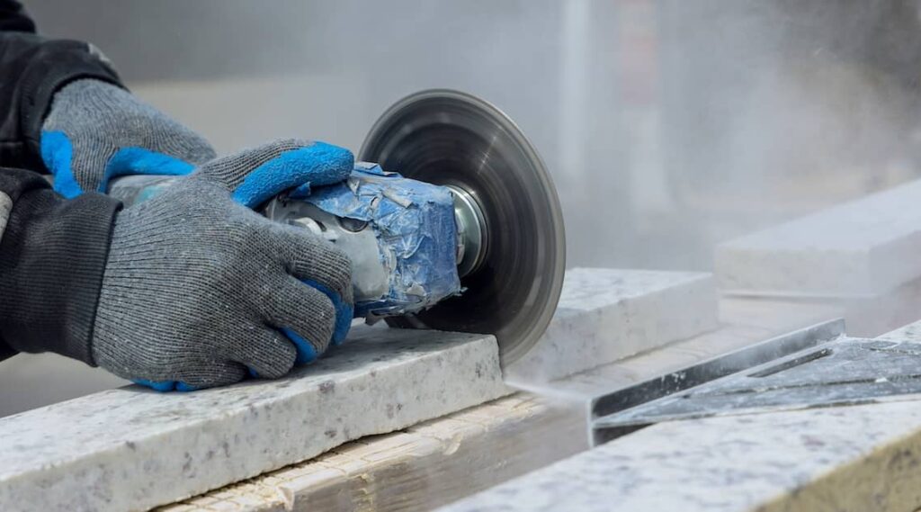Worker sawing benchtop, releasing crystalline silica dust into the air | Henry Carus + Associates