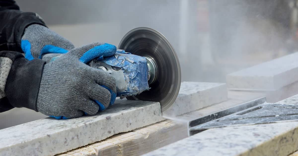 Worker sawing benchtop, releasing crystalline silica dust into the air | Henry Carus + Associates