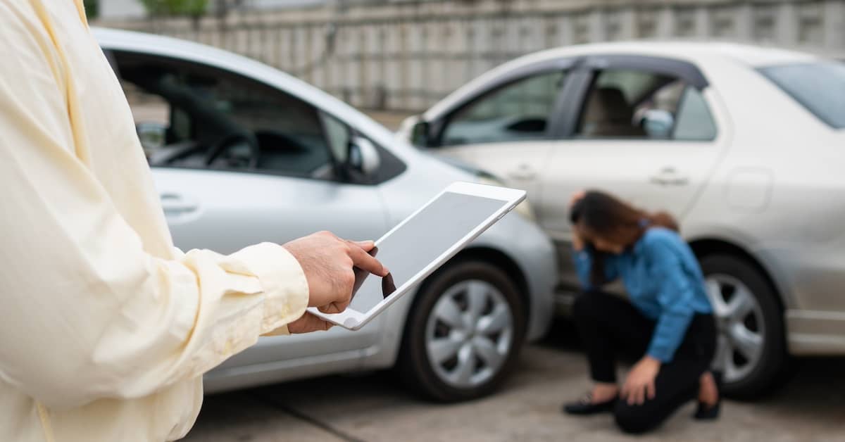 Investigator determining contributory negligence for an auto accident with distraught woman in the background | Henry Carus + Associates