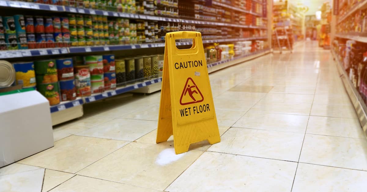 Caution: Wet Floor sign in the aisle of a supermarket | Henry Carus + Associates