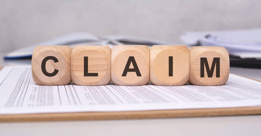 Wooden blocks spelling out the word 'Claim' on top of insurance documents | Henry Carus + Associates