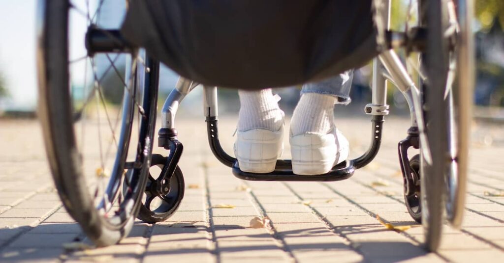 Feet of a person in a wheelchair on a public footpath | Henry Carus + Associates