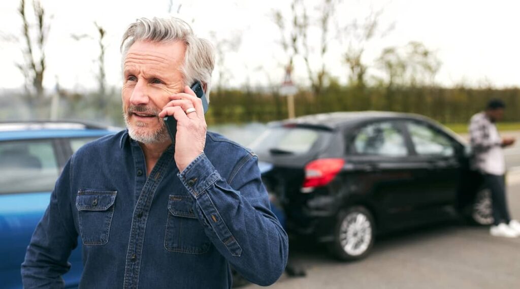 Middle-aged man calling emergency services after a road accident | Henry Carus + Associates