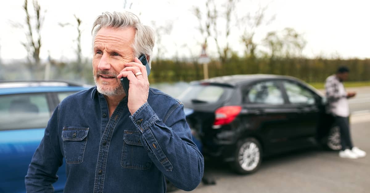 Middle-aged man calling emergency services after a road accident | Henry Carus + Associates